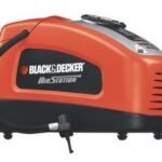 A Black and Decker air pump sitting near a car tire in a garage.