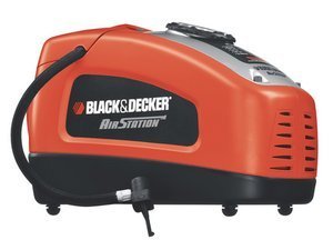 A Black and Decker air pump sitting near a car tire in a garage.