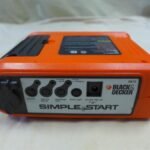 A professional car battery charger connected to a battery in a home garage.