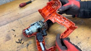 A cordless drill sitting on a workbench awaiting repair in a bright workshop.