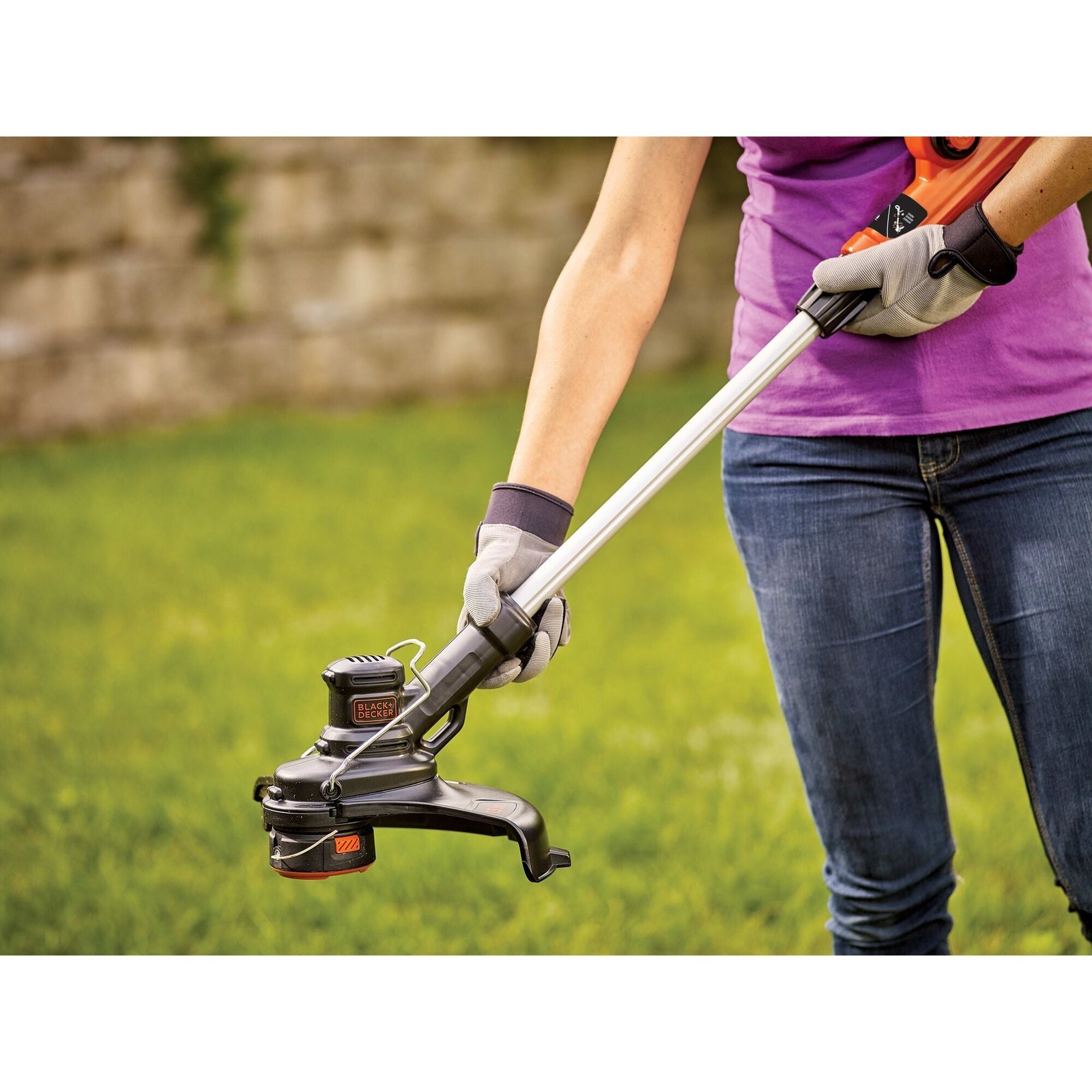 An open instruction manual for a cordless strimmer placed on a workbench.