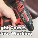 A cordless drill with a glowing LED light sits on a workshop bench.