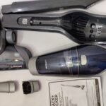 A disassembled cordless handheld vacuum cleaner on a wooden table.