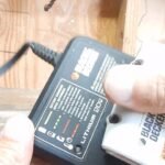 A cordless battery charger and battery unit on a clean workshop workbench.