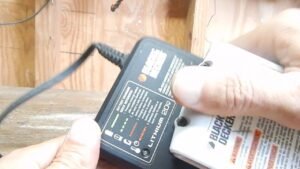 A cordless battery charger and battery unit on a clean workshop workbench.