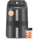 A modern black air fryer sitting on a clean white kitchen countertop.