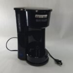 A modern black coffee maker sits on a kitchen counter for troubleshooting.