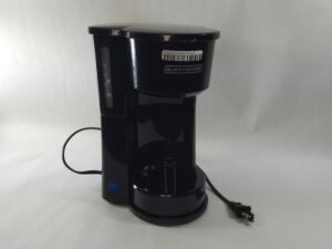 A modern black coffee maker sits on a kitchen counter for troubleshooting.