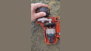 A modern cordless grass trimmer resting on a green lawn for garden maintenance.