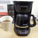 A modern drip coffee maker on a clean kitchen counter in natural light.