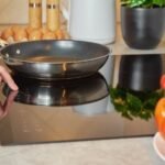 A Ninja pan sitting on a modern induction hob in a bright kitchen.