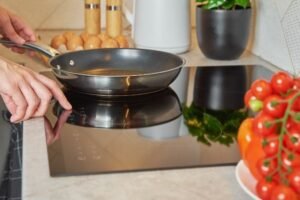 A Ninja pan sitting on a modern induction hob in a bright kitchen.