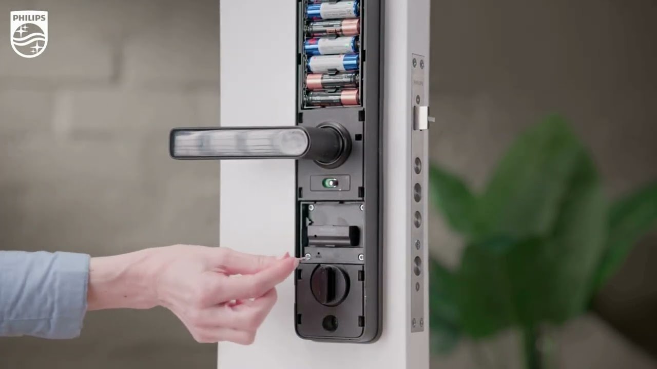 A person performing maintenance on a smart door lock to troubleshoot power issues.