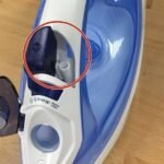A modern Philips iron sits on an ironing board in a bright laundry room.
