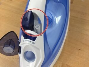A modern Philips iron sits on an ironing board in a bright laundry room.