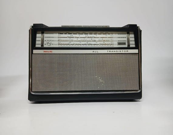 Hands troubleshooting a Philips radio by checking the power cord and volume.
